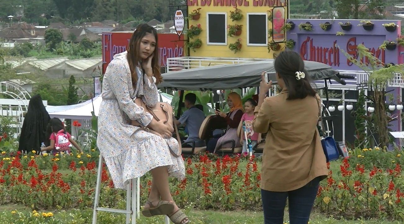 seorang pengunjung Florawisata San Terra de Lafonte  tengah berfoto di tengah taman bunga 