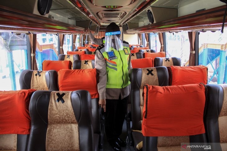 Petugas kepolisian  memeriksa armada bus dengan memakai pelindung wajah (face shield) di hari pertama beroperasinya kembali Terminal Purabaya, Bungurasih. (foto:Antara)