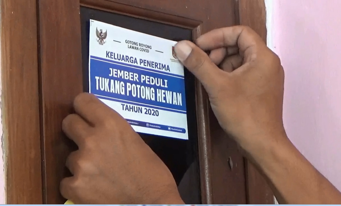 Petugas menempkan stiker di pintu rumah para tukang potong hewan yang menerima bantuan sosial. (foto/metrotv)