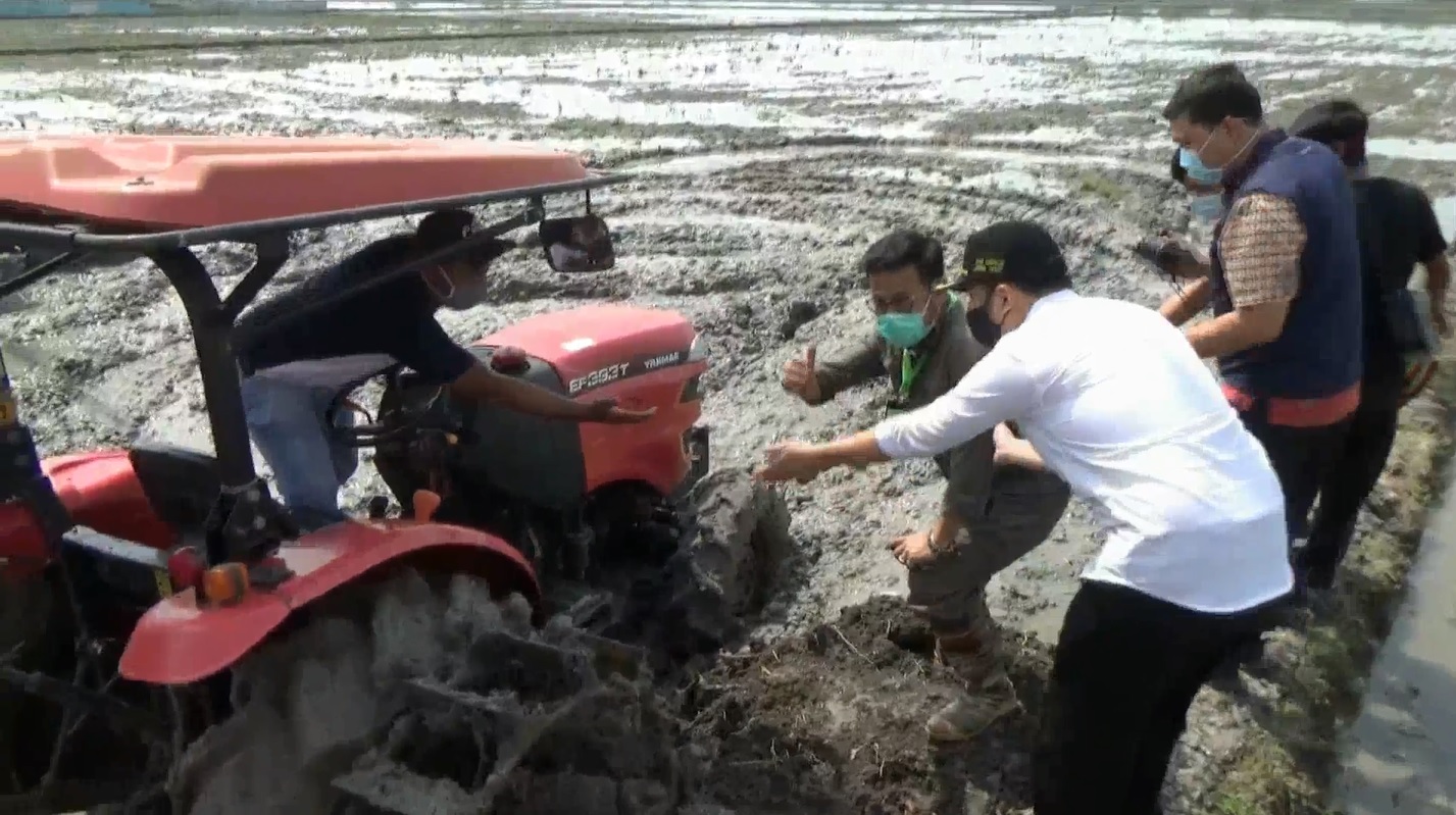 Menteri pertanian Syahrul Yasin Limpo dibantu oleh Wakil Gubernur Jatim Emil Dardak saat mencoba traktor di lahan pertanian di Tuban (foto/metrotv)