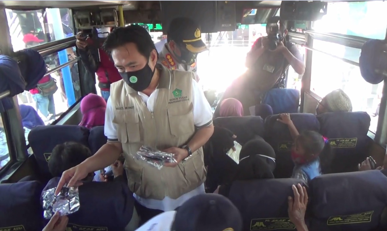 Kepala Gugus Tugas Penanganan Covid-19 Sidoarjo, Nur Ahmad Syaifuddin dan Kapolres Sidoarjo Kombes Sumardji membagikan masker kepada penumpang bus. (foto/metrotv) 