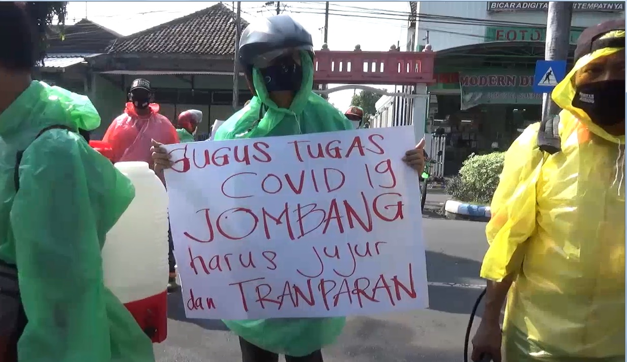 Salah satu peserta unjuk rasa membentangkan poster menuntut transparasi anggaran penanganan covid-19 di Jombang. (foto/metrotv) 