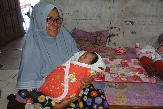 Supini menggendong bayi perempuan yang ia temukan di teras rumahnya. Diduga bayi tersebut sengaja dibuang oleh orang tuanya (foto/Metro tv)