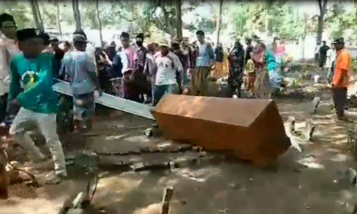 Ratusan warga  membanting peti jenazah yang digunakan untuk memakamkan pasien covid-19 di Kecamatan Lekok, Kabupaten Pasuruan. (foto/metrotv)