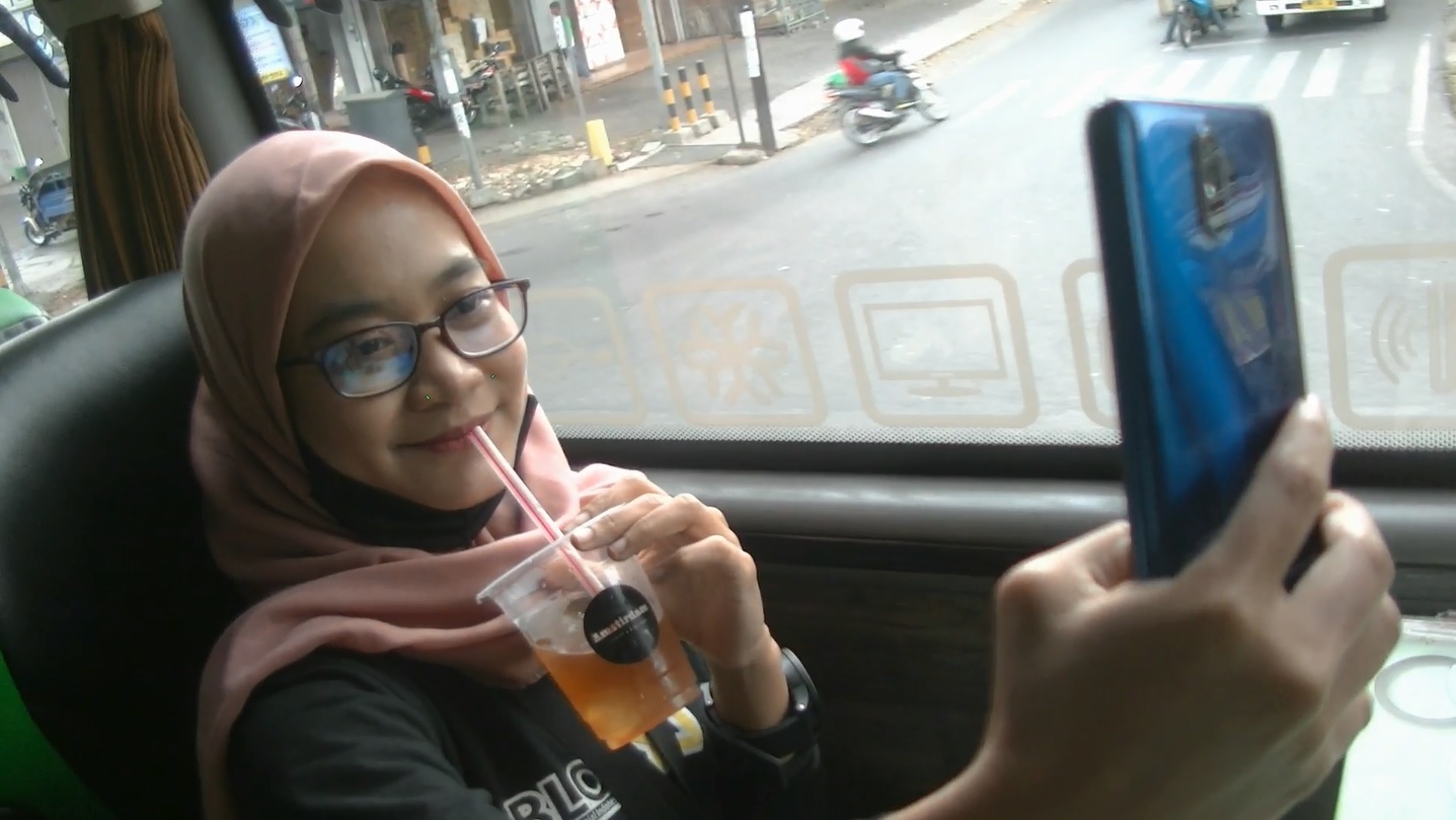 Salah seorang pengunjung kafe berjalan tengah menikmati kopi di atas bus menyusuri Kota Malang sambil ber swafoto (Foto / Metro tv)