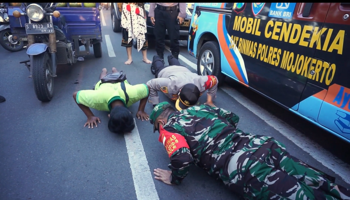 Kapolres Mojokerto AKBP Dony Alexander dan Dandim 0815 Mojokerto Letkol Infanteri Dwi Mawan Sutanto memberikan contoh push up kepada pelanggar protokol kesehatan (Foto / Metro TV) 