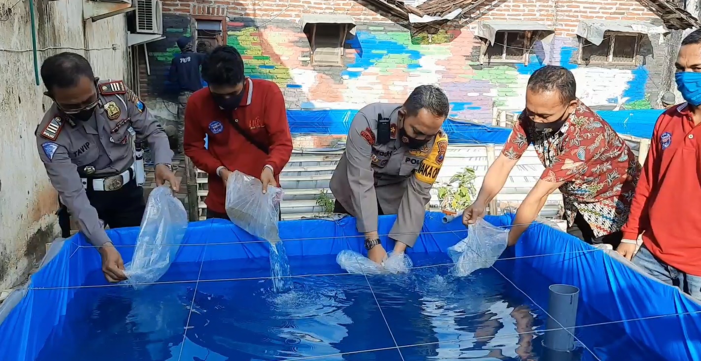 Wakapolres Probolinggo Kota Kompol Teguh (tengah) bersama Jurnalis Probolinggo Jawa Timur (Jispro) melepas ribuan benih ikan untuk mendukung program ketahanan pangan (Foto / Metro TV)
