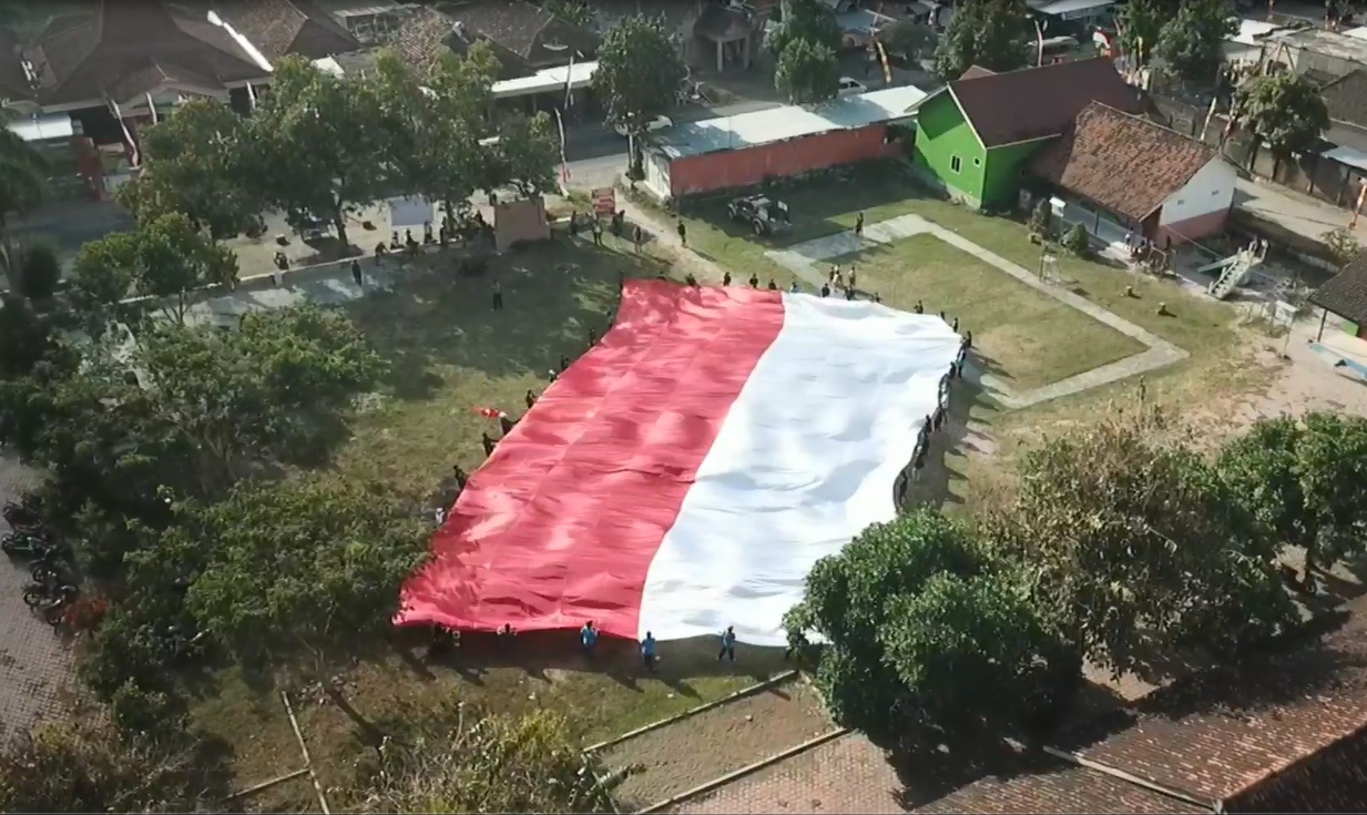 Bendera raksasa dibentangkan di lapangan Desa Gamping sebelum diarak menuju Tebing Wajakensis Tulungagung. (foto/metrotv)