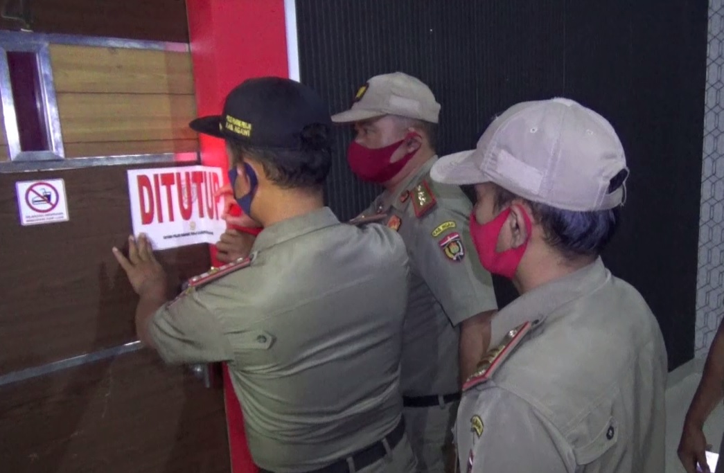 Petugas Satpol PP memasang stiker di pintu room karaoke. (metrotv)