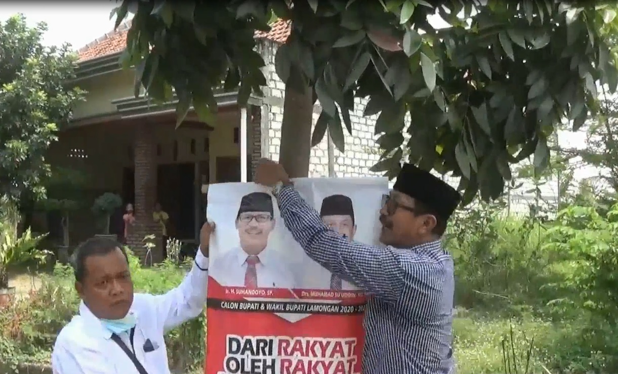 Sahandoyo mencabut satu persatu poster bergambar dirinya di jalan Desa Kebet,  Kecamatan Lamongan. (metrotv)