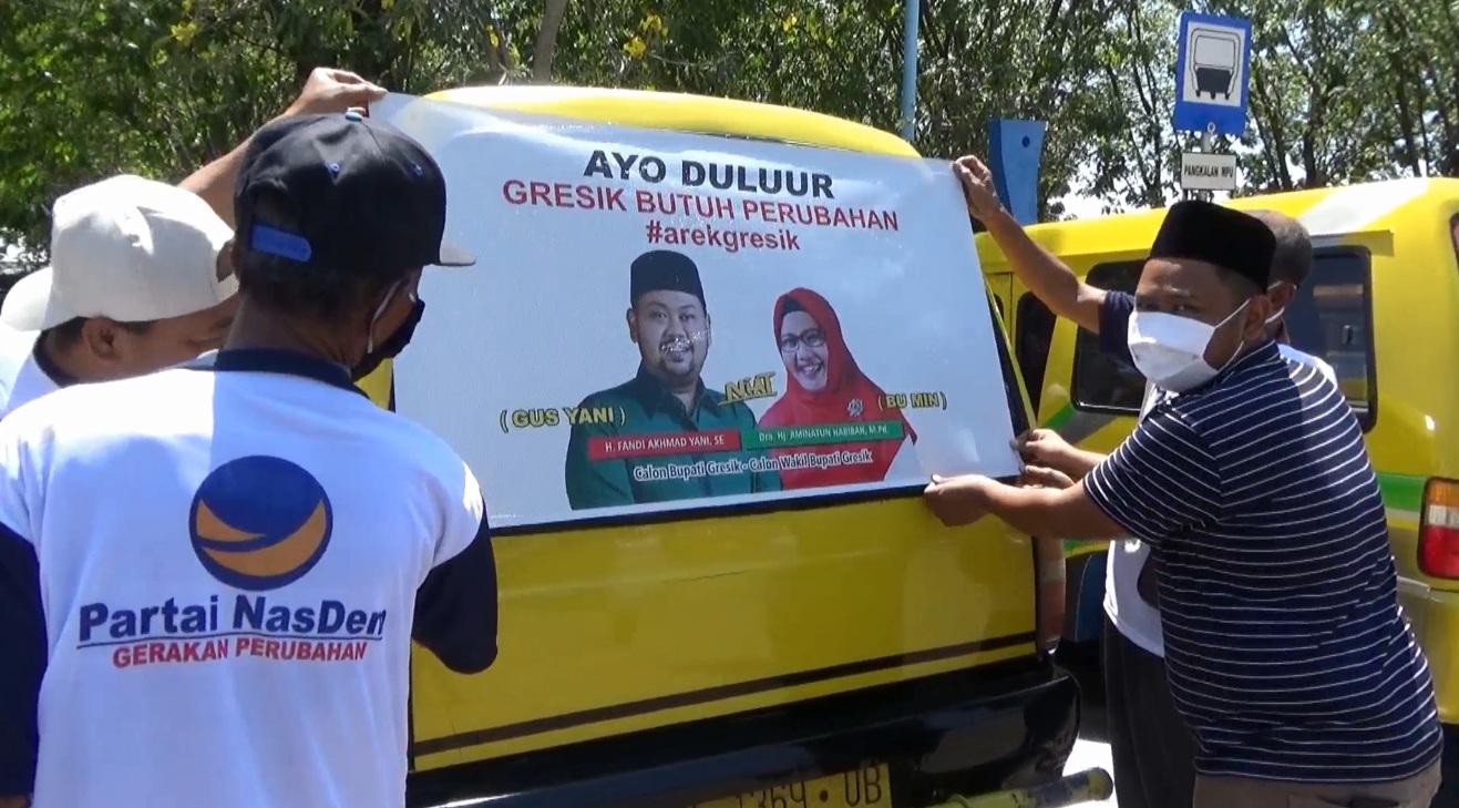 Gus Yani, calon bupati Gresik menempelkan stiker pasangan Niat di belakangan kaca mobil sopir angkot (Foto / Metro TV)