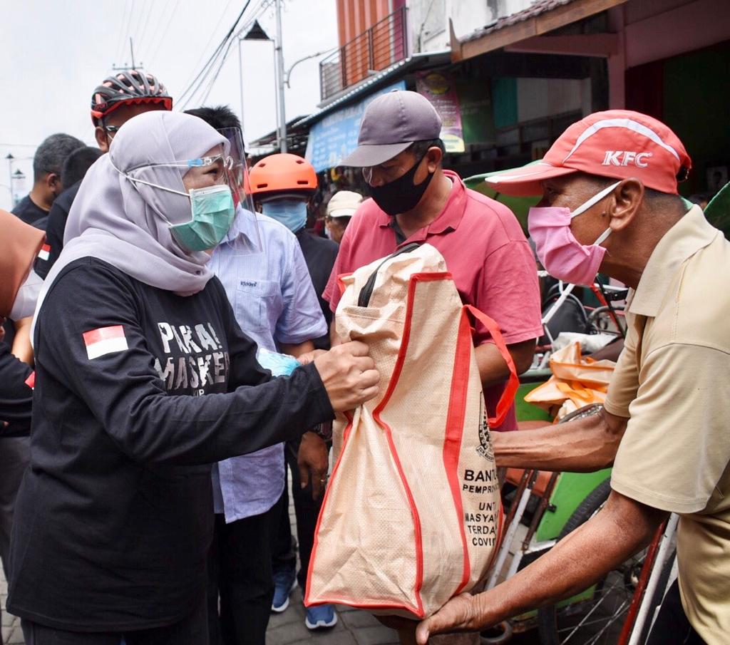 Gubernur Jawa Timur Khofifah Indar Parawansa mmeberikan bantuan sembako kepada warga sambil gowes (Foto / Clicks.id)