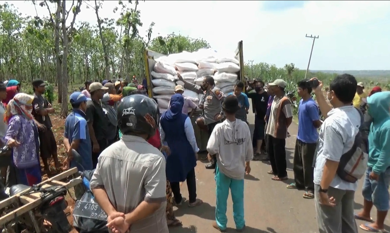 Petugas kepolisian mencoba menenangkan para petani yang menghadang truk pengangkut pupuk bersubsidi. (metrotv)