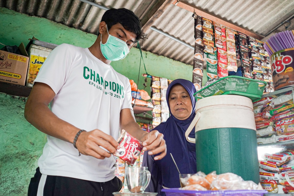 Andhika Ramadhani saat membantu ibunya di warung (Foto / Persebaya)