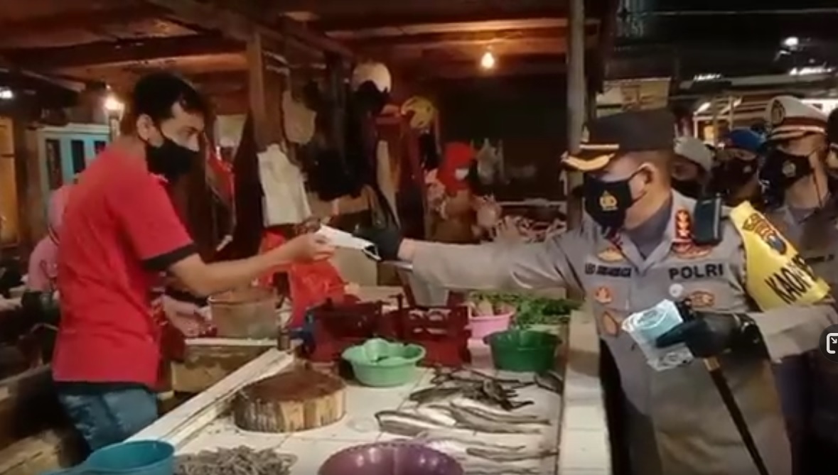Pembagian masker diilakukan aparat kepolisan di salah satu pasar tradisional Kota Malang. (metrotv)