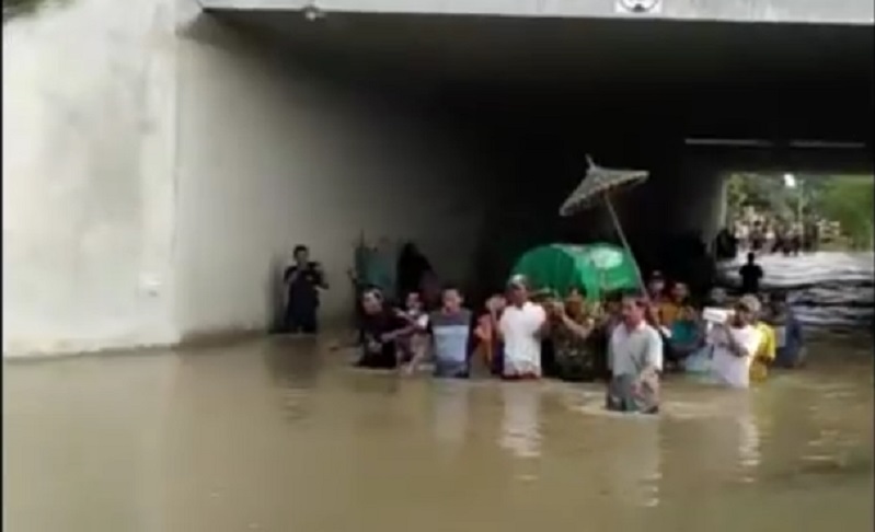 Warga Desa Bandarkedungmulyo mengantarkan jenazah di tengah kepungan banjir (Foto / Metro TV)