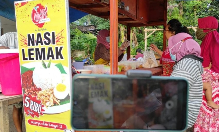 Sambil direkam untuk diupload di Youtube, Ika nampak sibuk melayani pelanggan untuk membeli  nasi lemak buatannya (Foto / Istimewa)