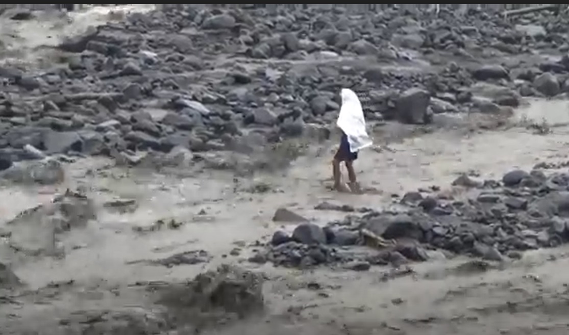 Warga desa terpaksa berjalan kaki sekitar 100 meter di atas banjir lahar Gunung Semeru. (metrotv)