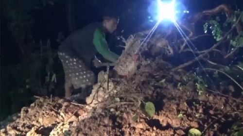 Petugas dan dibantu warga membersihkan material longsor yang menutup jalan Raya Kare (Foto / Metro TV)