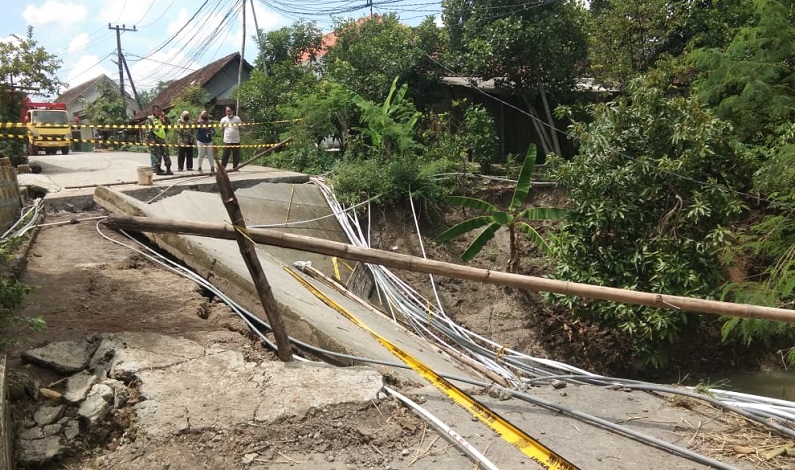 Warga memasang garis dilarang melintas di Jembatan Jangklot yang ambruk usai diterjang banjir bandang (Foto / Metro TV)