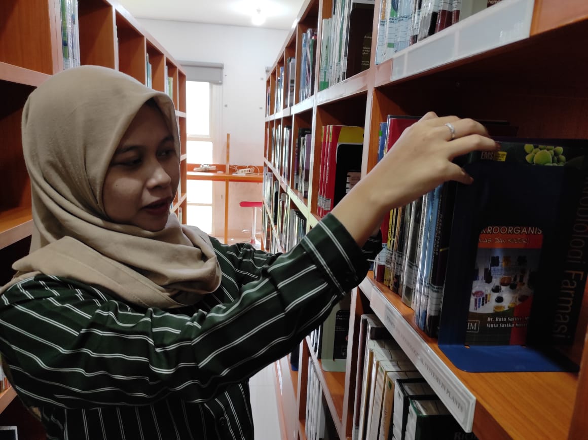 Salah satu pustakawan Unusa sedang mencarikan buku yang akan dipinjam mahasiswa melaluli layanan delivery book (Foto / Clicks.id)