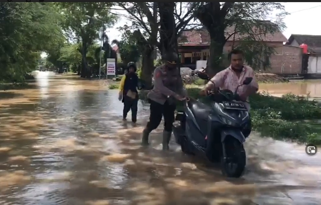 Anggota kepolisian membantu warga mendorong motor mogok akibat banjir. (metrotv)