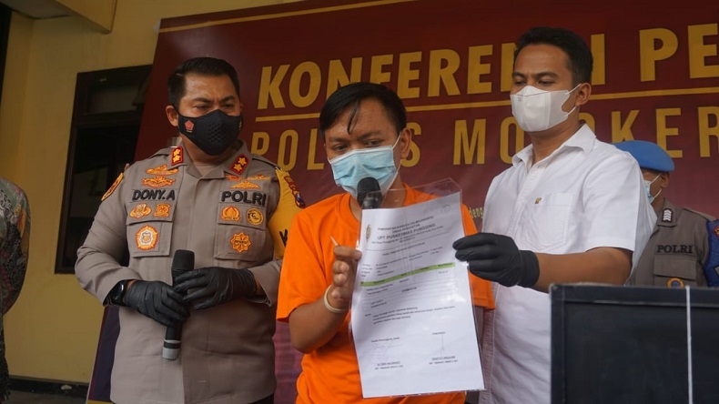 Kapolres Mojokerto, AKBP Dony Alexander bersama tersangka Dwi Wahyu menunjukkan barang bukti surat antigen palsu yang diperjual belikan (Foto / Metro TV)