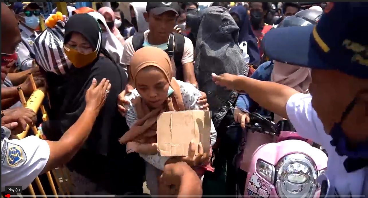 Seorang ibu mengendong bayi berusaha keluar dari desakan antrian penumpang kapal di Pelabuhan Kalianget. (metrotv)