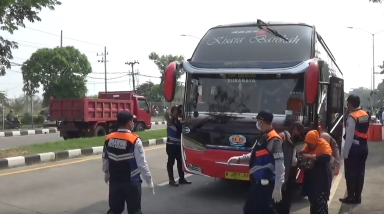 Petugas menghentikan bus penumpang di jembatan Suramadu untuk dilakukan swab (Foto / Metro TV)