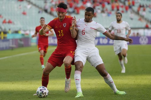 Gelandang Wales Kieffer Moore berduel dengan bek Swiss Manuel Akanji. (Darko Vojinovic / POOL / AFP)