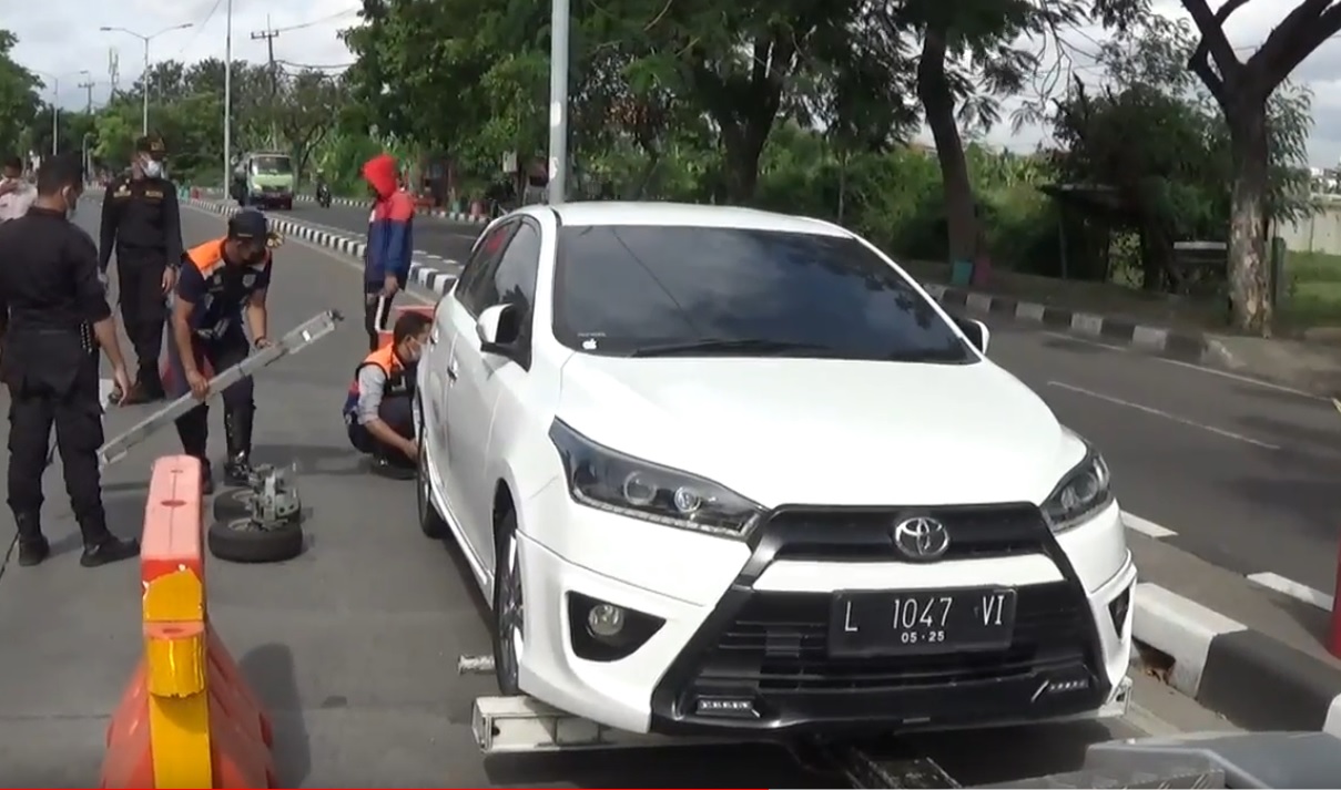 Petugas menderek salah satu mobil yang ditinggal pemiliknya di Pos Penyekatan Suramadu. (metrotv)