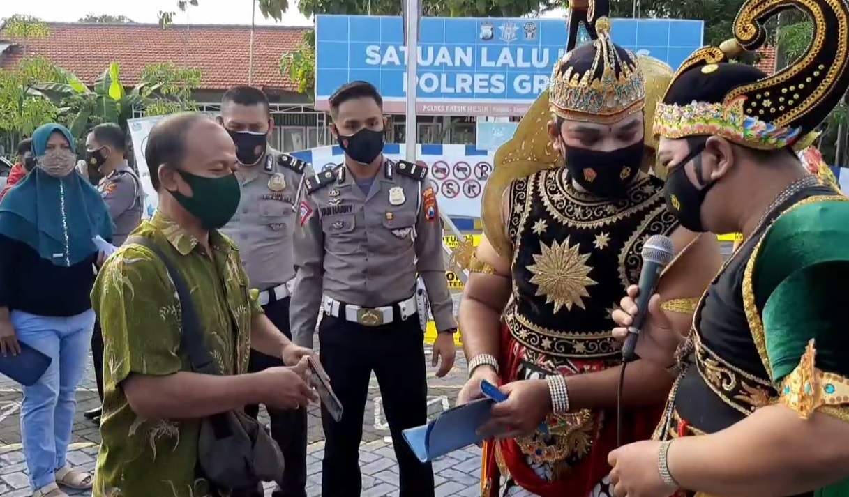 Petugas berbaju Arjuna dan Gatotkaca memeriksa sertifikat vaksin pemohon SIM. (metrotv)