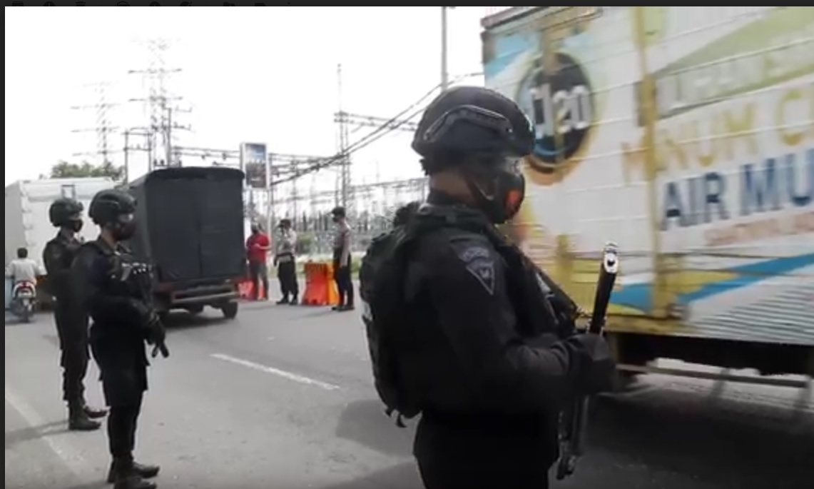 Aparat bersenjata lengkap berjaga di lokasi penyekatan di depan tugu pintu masuk Kabupaten Bangkalan. (metrotv)