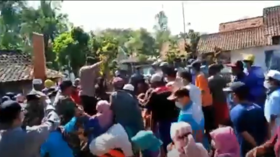 Petugas kepolisan berusahan menenangkan warga yang merusak peti jenazah covid-19 saat pemakaman. (metrotv)