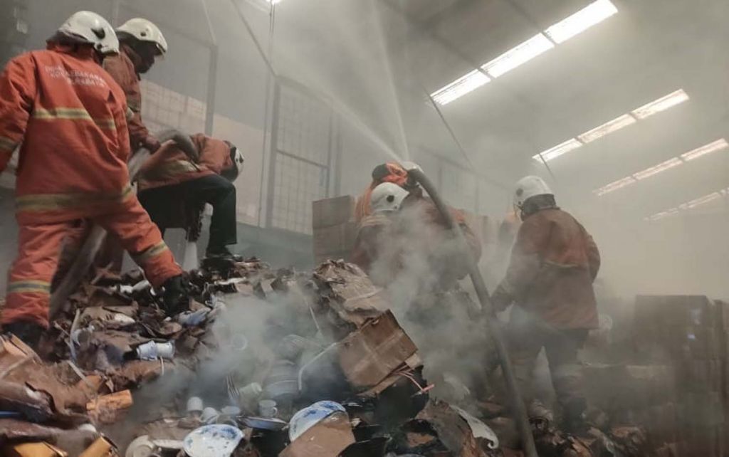 Petugas Pemadam Kota Surabaya saat mencoba memadamkan api yang membakar gudang pecah belah (Foto / Istimewa)