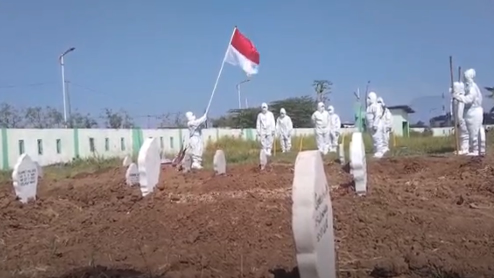 Upacara bendera digelar sejumlah relawan penggali kubur jenazah covid di TPU  Pagu Indah, Kelurahan Manisrejo, Kecamatan Taman, Madiun. (metrotv)