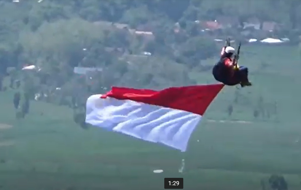 Atlet paralayang Magetan menerbangkan bendera merah putih dari puncak Gunung Bungkuk. (metrotv)
