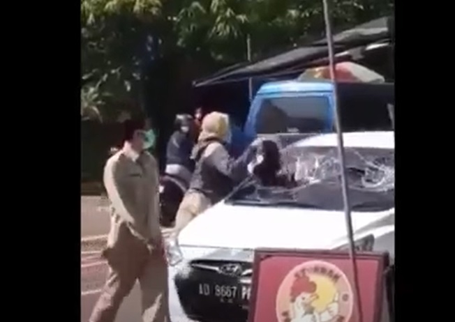 Perempuan berbaju ASN menghancurkan kaca mobil di sekitar Jalan  Ronggowarsito, Kelurahan Karangtengah, Kabupaten Ngawi. (metrotv) 