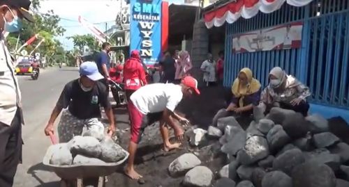 Sejumlah guru dan pegawai sekolah membersihkan batu dan pasir untuk bisa masuk. (metrotv)