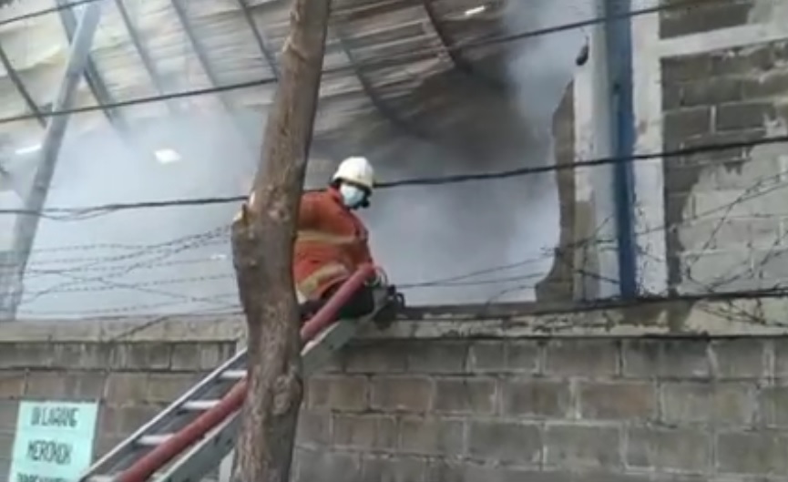 Petugas pemadam kebakaran menerobos kepulan asap di gudang yang terbakar. (metrotv)