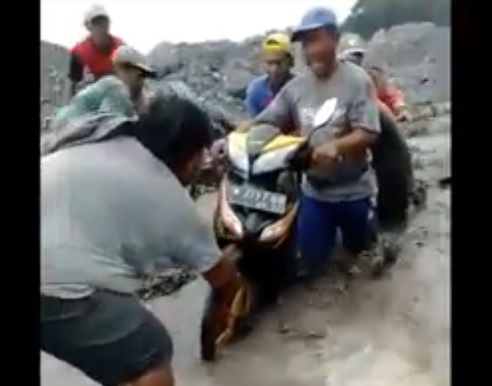 Para penambang pasir menyelamatkan motor dari terjangan banjir lahar dingin Gunung Semeru. (metrotv)