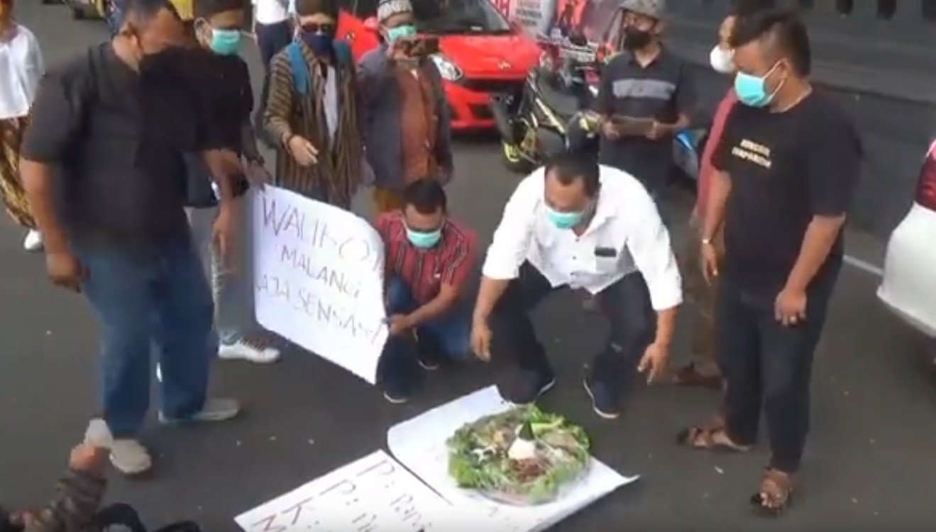Aktivis membawa tumpeng dan dupa untuk ritual buang sial terhadap Walikota Kota Malang, Sutiaji yang melanggar PPKM (Foto / Metro TV)