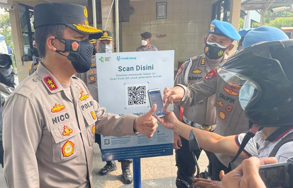 Kapolda Jatim, Irjen Pol Nico Afinta meminta salah satu pengunjung Polda Jatim melakukan scan QR Code Aplikasi PeduliLindungi (Foto / Metro TV)