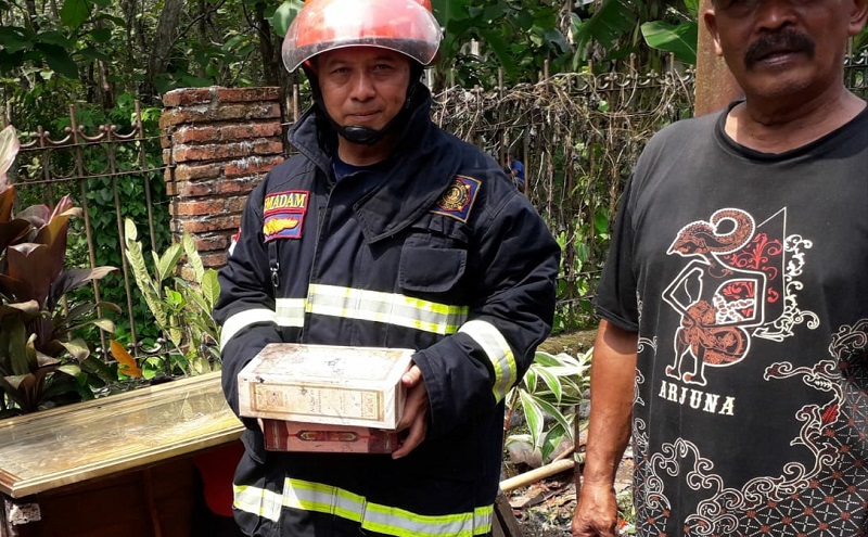 Petugas pemadam kebakaran menunjukkan 2 Alquran yang utuh dari sisa kebakaran pabrik rokok rumahan di Malang (Foto / Metro TV)