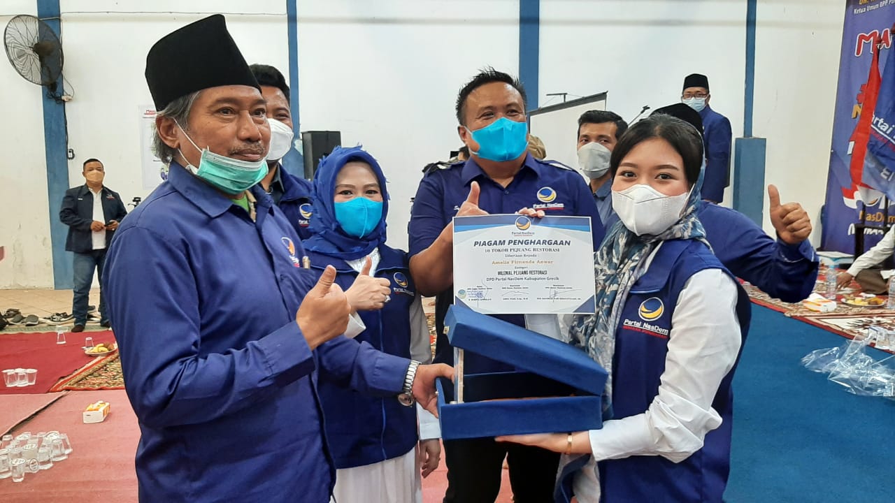Ketua DPD NasDem Gresik, Syaiful Anwar (tengah) menyerahkan penghargaan penghargaan kepada Amelia Firnanda Anwar, salah satu pejuang restorasi yang menginsiparasi milenial (Foto / Metro TV)