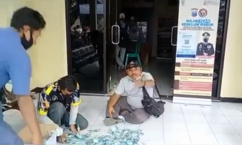 Tangkapan layar pengacara hamburkan uang di depan polisi (Foto / Metro TV)