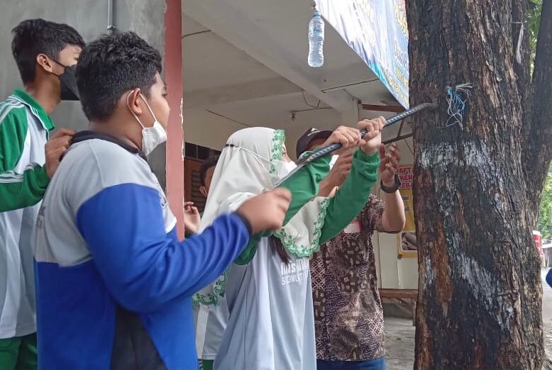 Sejumlah siswa MTs Ma’arif Sidomukti Giri Gresik mencabuti paku yang menempel di pohon (Foto / Istimewa)
