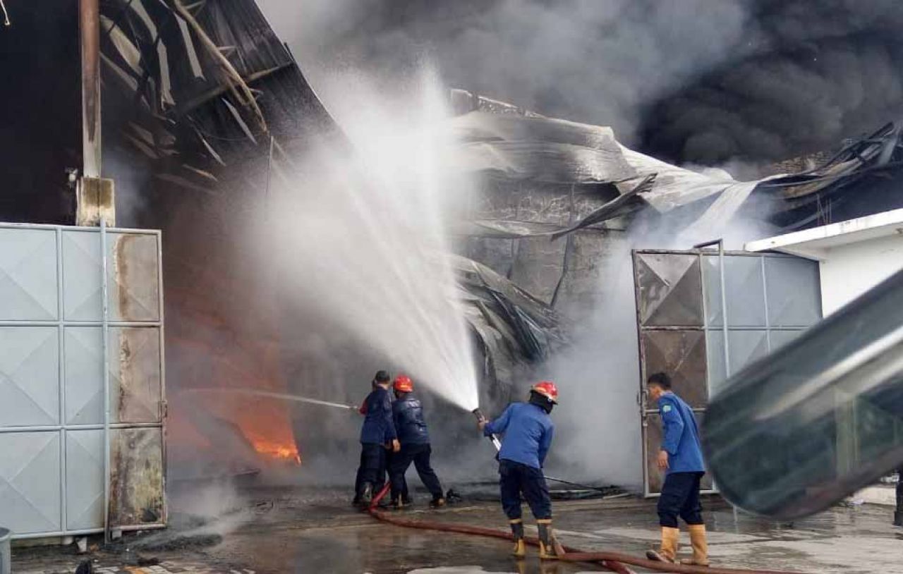 Petugas mencoba memadamkan api yang menghanguskan pabrik palet plastik di Sidoarjo (Foto / Metro TV)