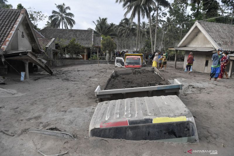 Warga mengamati truk pengangkut pasir yang tertimbun abu Gunung Semeru di Desa Sumberwuluh, Kabupaten Lumajang, Provinsi Jawa Timur, Minggu (5/12/2021). (ANTARA)