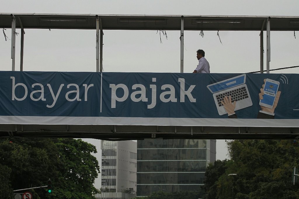 ejalan kaki melintasi papan sosialisasi pembayaran pajak secara online. FOTO: MI/ARYA MANGGALA